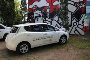 E-Auto vor der von Street Art Künstler Rebelzer bemalten Wand